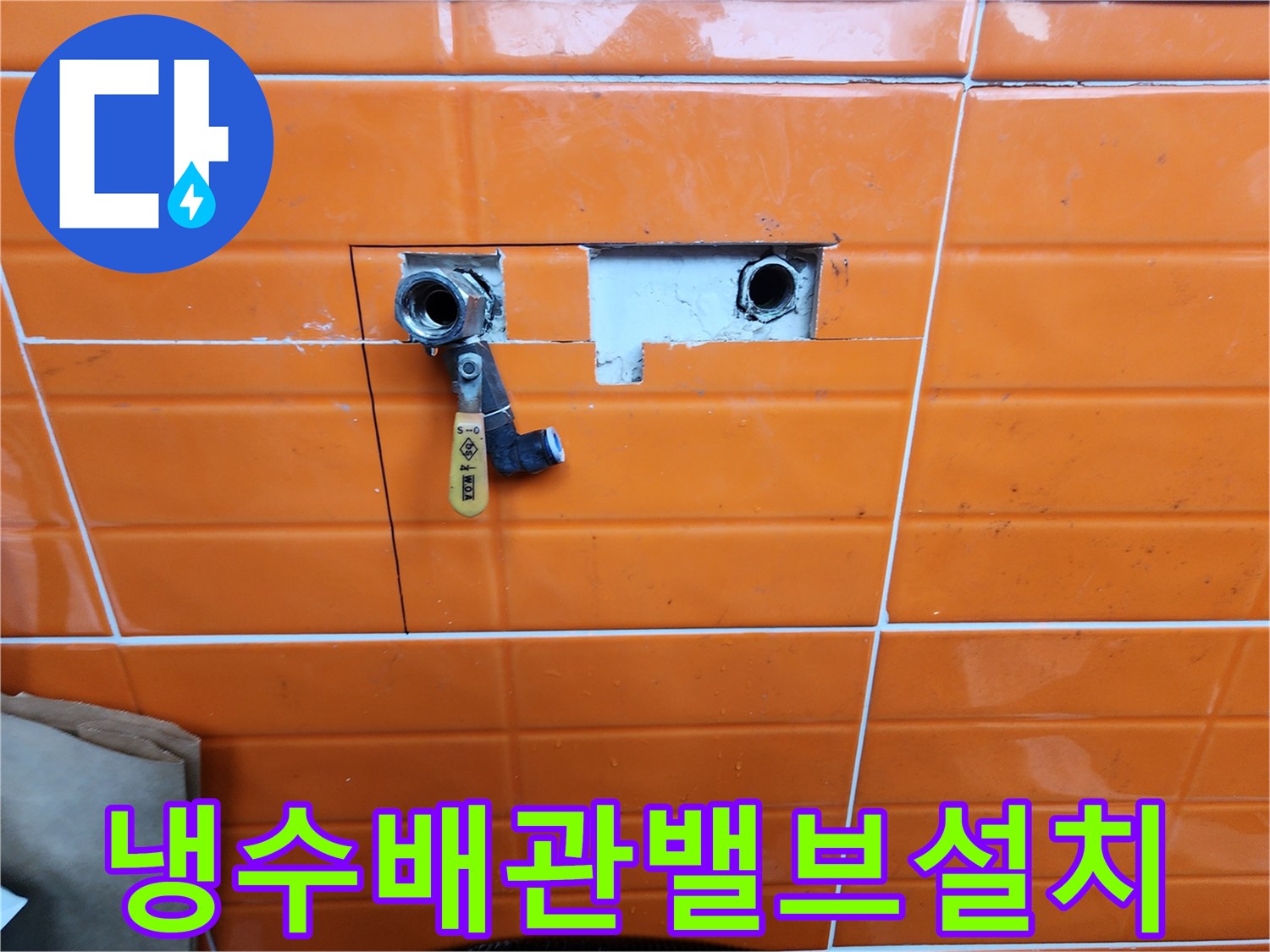 오렌지색-타일이-부분적으로-제거된-곳에-새로운-수도-밸브가-설치된-배관-수리-과정을-담은-사진입니다.