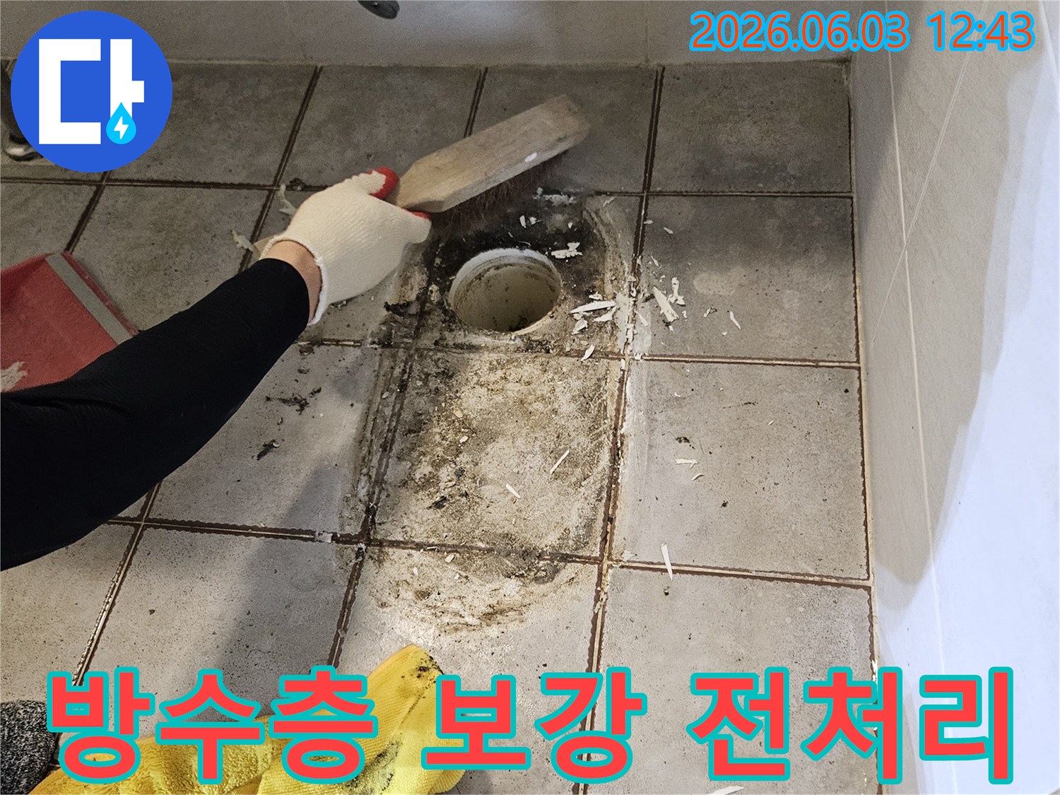 누수 공사 중-엔지니어가-욕실 바닥-배수구 주변의-오염된 이물질을-스크래퍼로-제거하는 모습