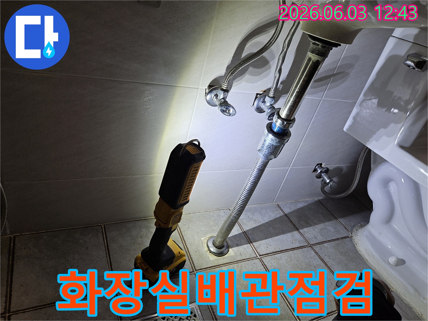 타일 바닥에 설치된 배관과-그 주변을 비추는-누수 탐지용 조명 장비가-정밀하게 작동하고 있습니다.