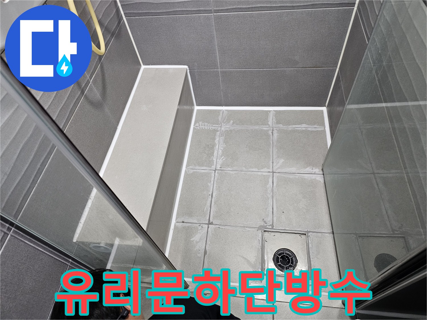 천호동 아파트 샤워실의 유리문 하단에-오래된 실리콘을 제거하고-새로운 방수 실리콘으로 교체하는 모습입니다.