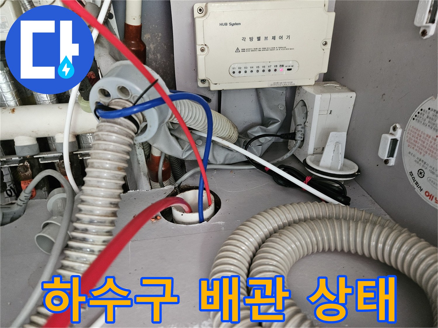바닥으로 연결된 흰색 주름관과 복잡한 배관 구조물