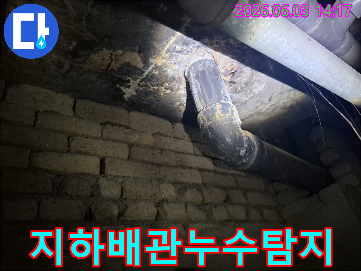 어두운 지하 공간에서-낡은 배관과-벽돌 벽에 발생한-누수 흔적을-조명으로 비춰-정밀하게 검사하는 모습