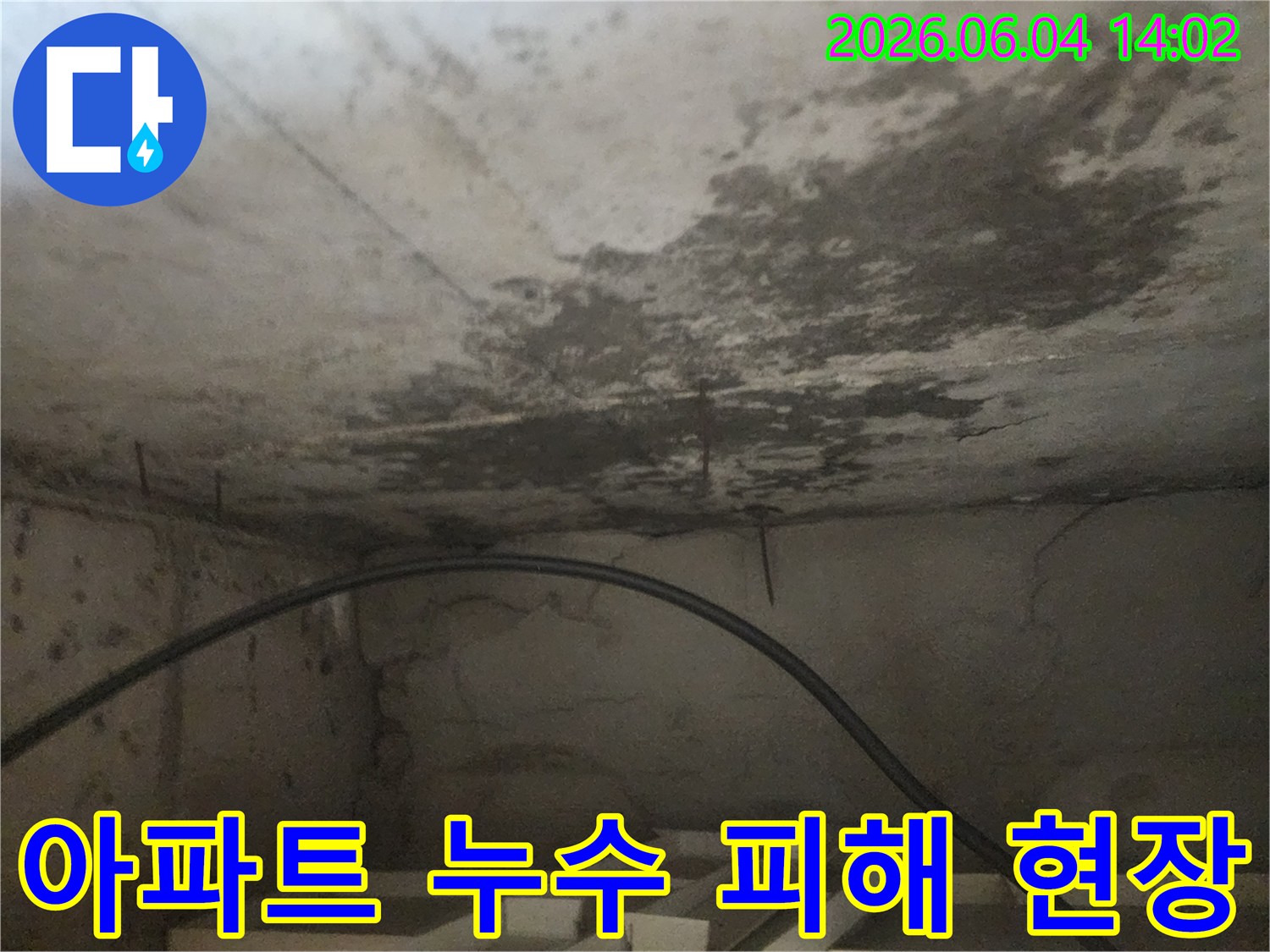 아파트 아래층 천장에 발생한-누수로 인한-심각한 물자국과-콘크리트 손상을 담은 사진입니다.