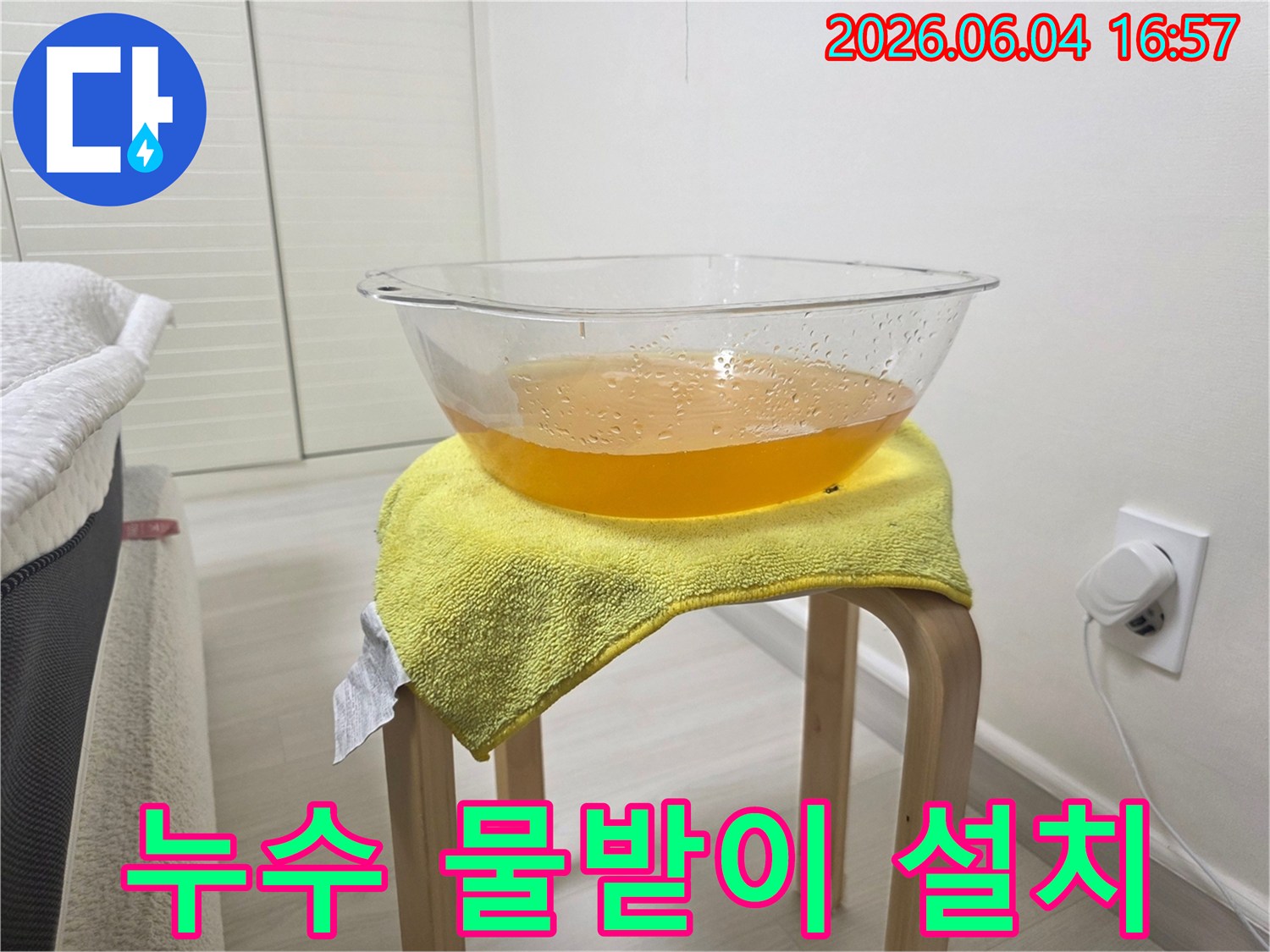 누수 발생 시-바닥 손상을 막기 위해-설치된 임시 물받이와-그 위에 놓인 노란 수건의 모습
