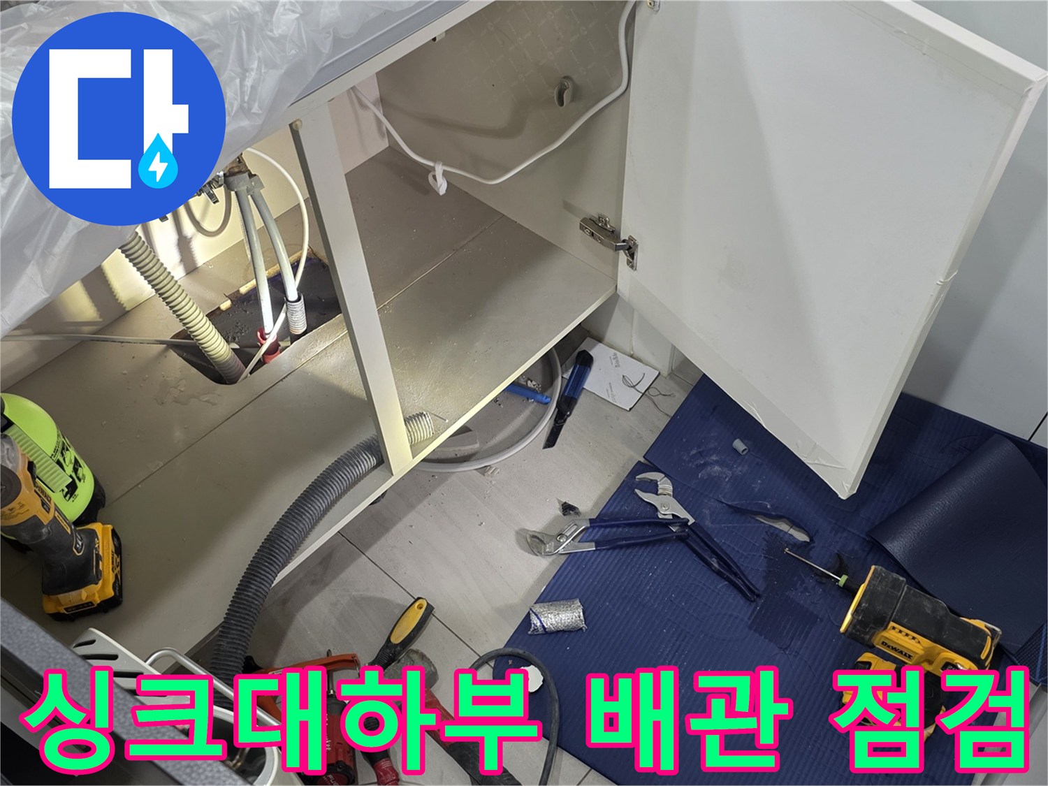 일산서구 주방 싱크대 하부장의 열린 문 사이로 보이는 배관과 작업 도구들
