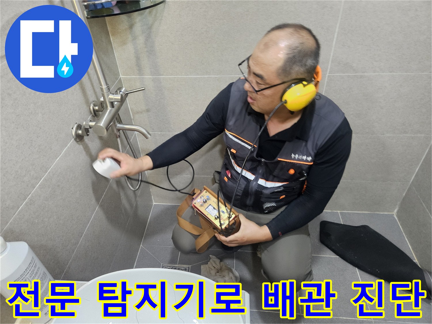 화장실 타일 벽면 근처에서 청음 장비를 이용해 누수 지점을 정밀하게 조사하는 장면입니다.