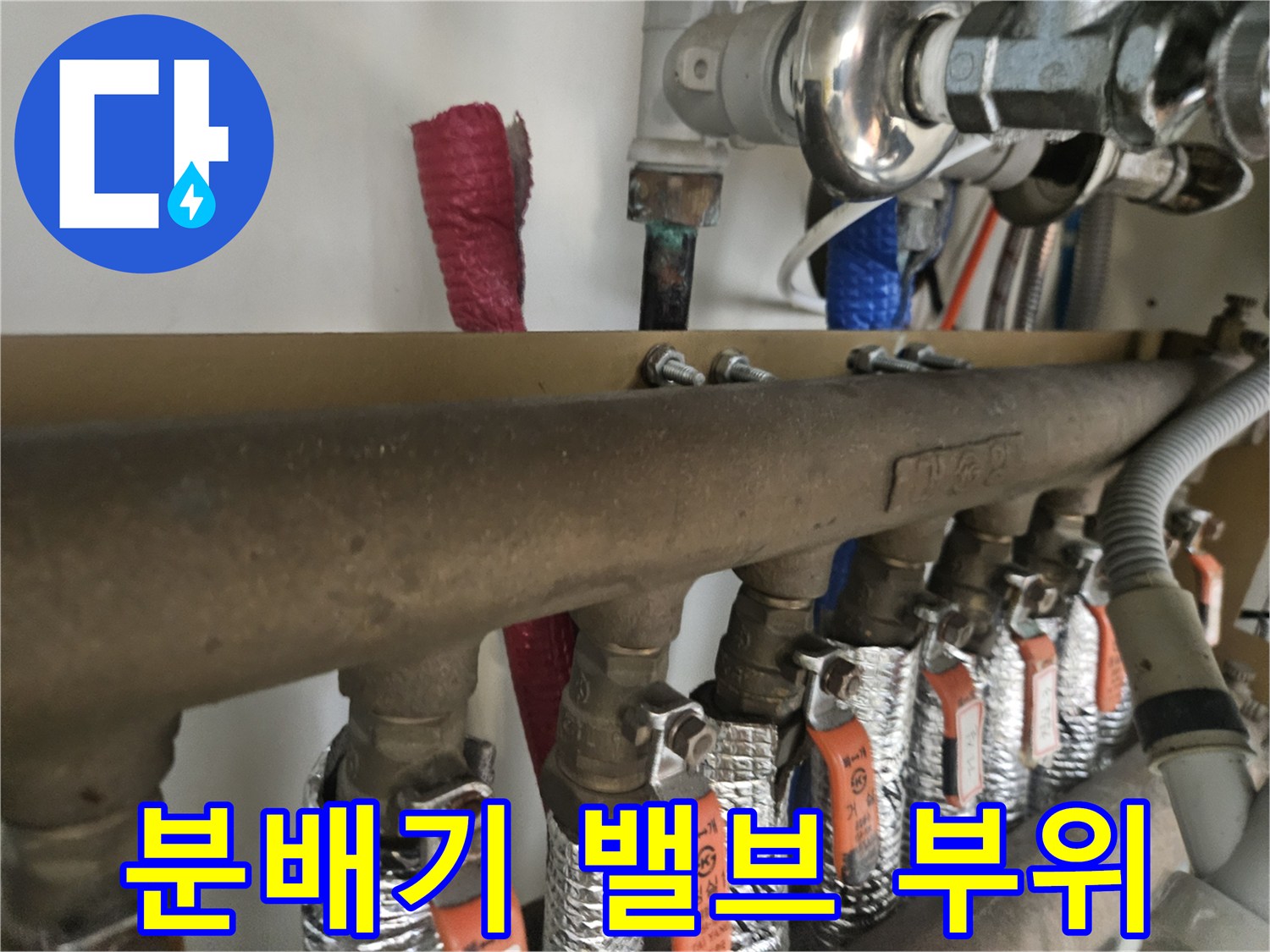 은박 마감재로 감싸진 난방 배관과 금속제 분배기 연결 상세 사진입니다.