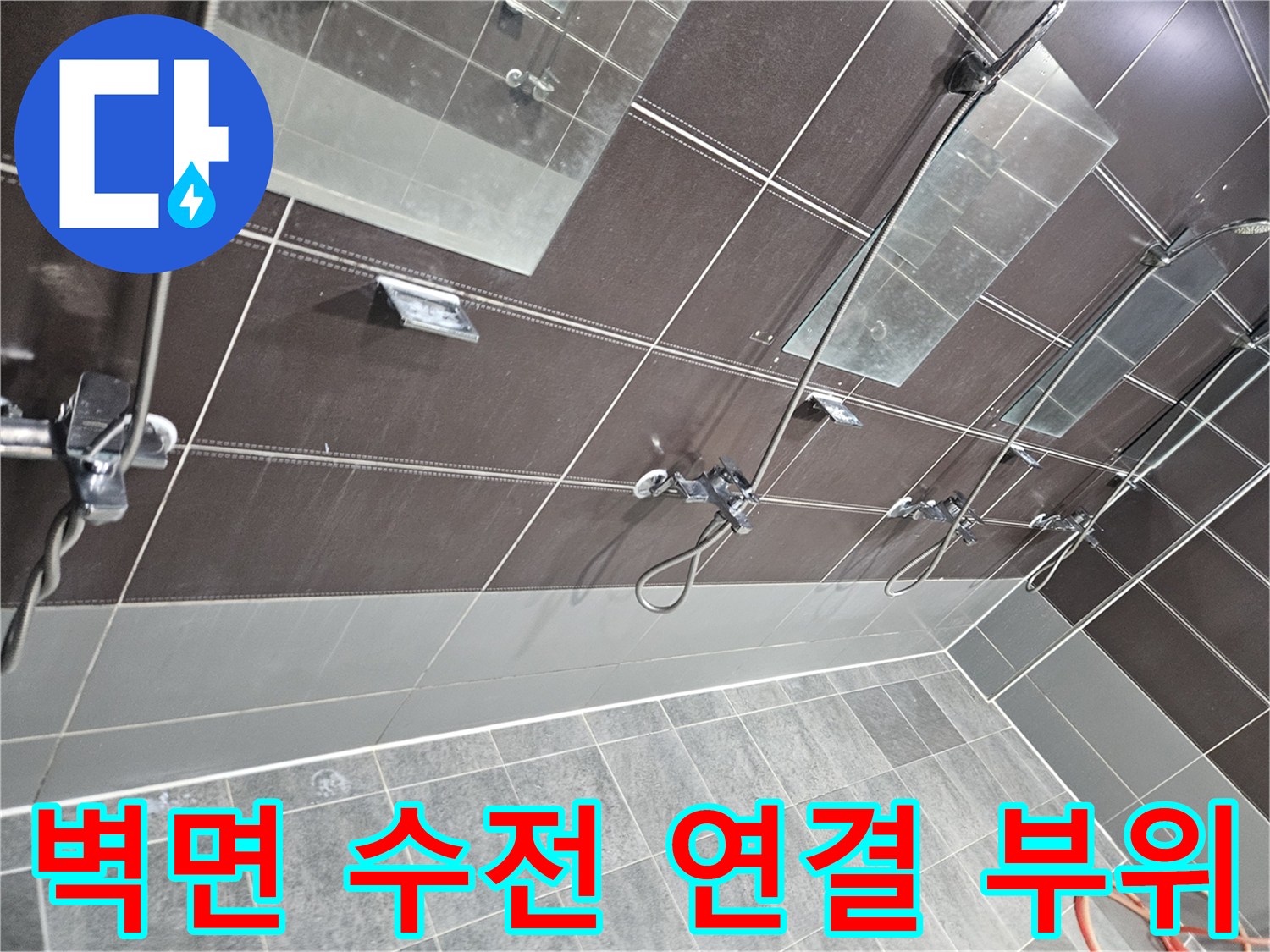 어두운 톤의 샤워실 벽면 타일과 설치된 수전의 상태를 나타내는 사진
