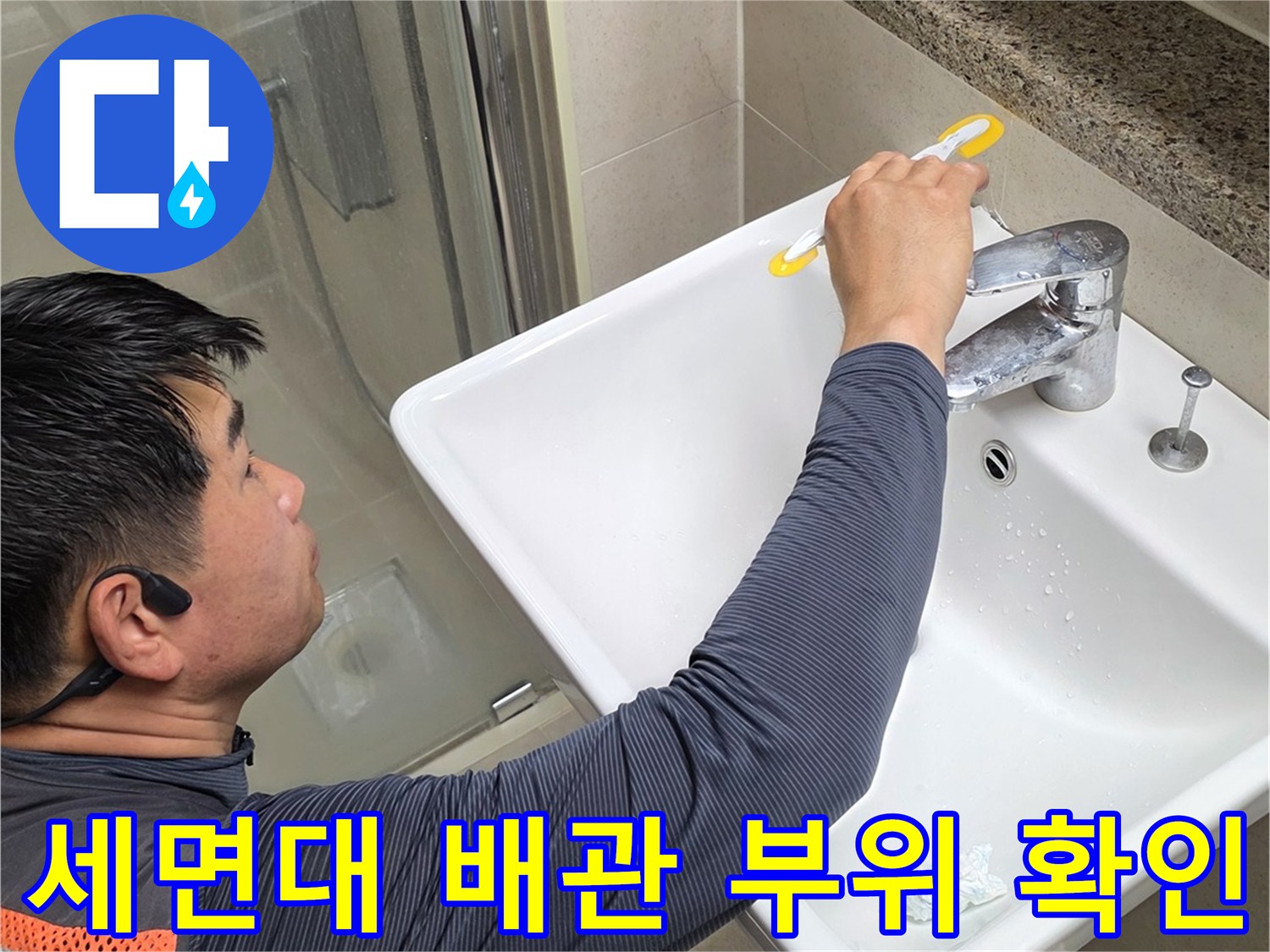 세면대 아래쪽 배관 연결부를 손으로 만지며 검사하는 모습