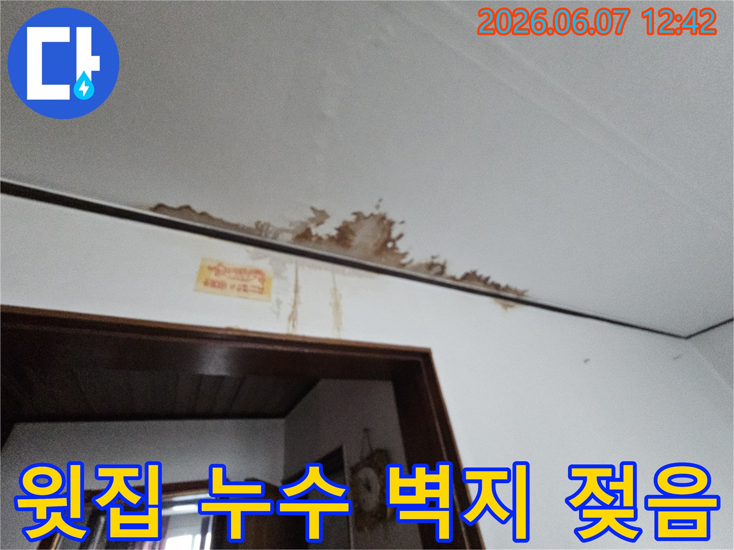 윗집 누수로 인해 천장 벽지가 젖고 갈색 얼룩이 심하게 발생한 주택 내부 모습입니다