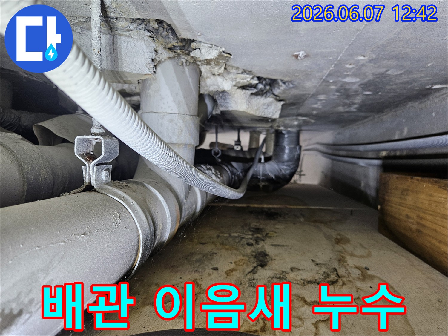 배관 이음새에서 물이 새어 나와-바닥에 물자국과-습기가 가득한-누수 현장의 모습입니다.
