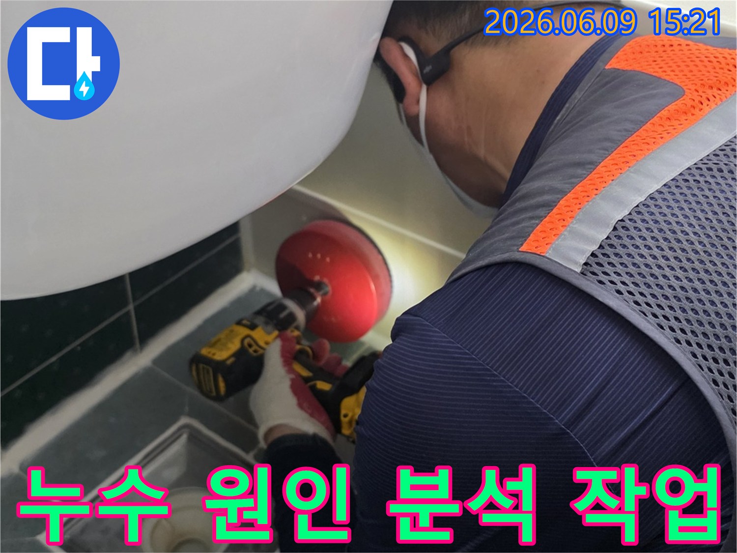 안전-조끼를-입은-전문가가-욕실-배수구-근처의-누수-지점을-정확히-파악하기-위해-전동-공구를-사용하여-작업하는-장면