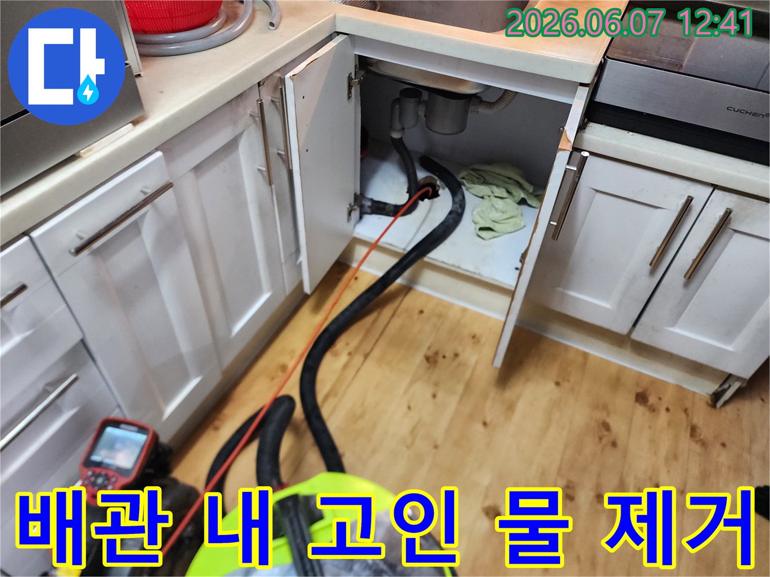 싱크대 하부 배관 틈으로 석션 호스를 투입한 장면입니다.