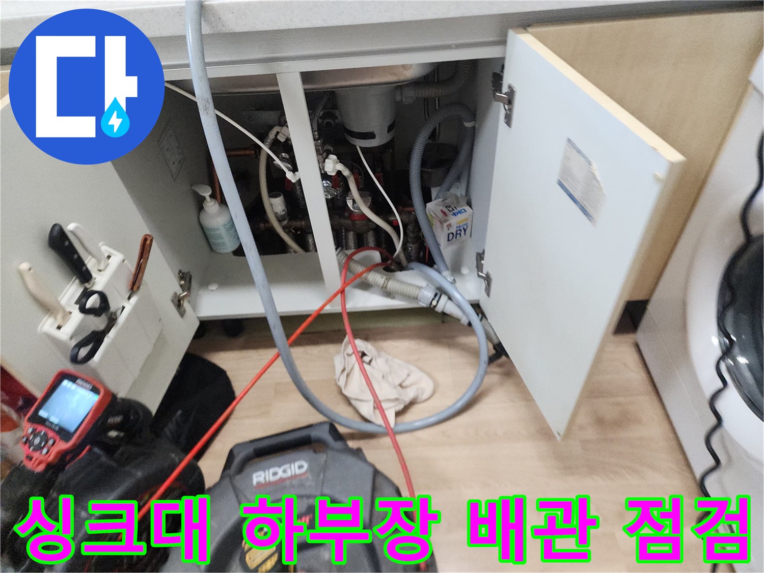 남양주 평내동 싱크대 하부장 내부의 복잡한 배관 구조와 작업 장비 모습