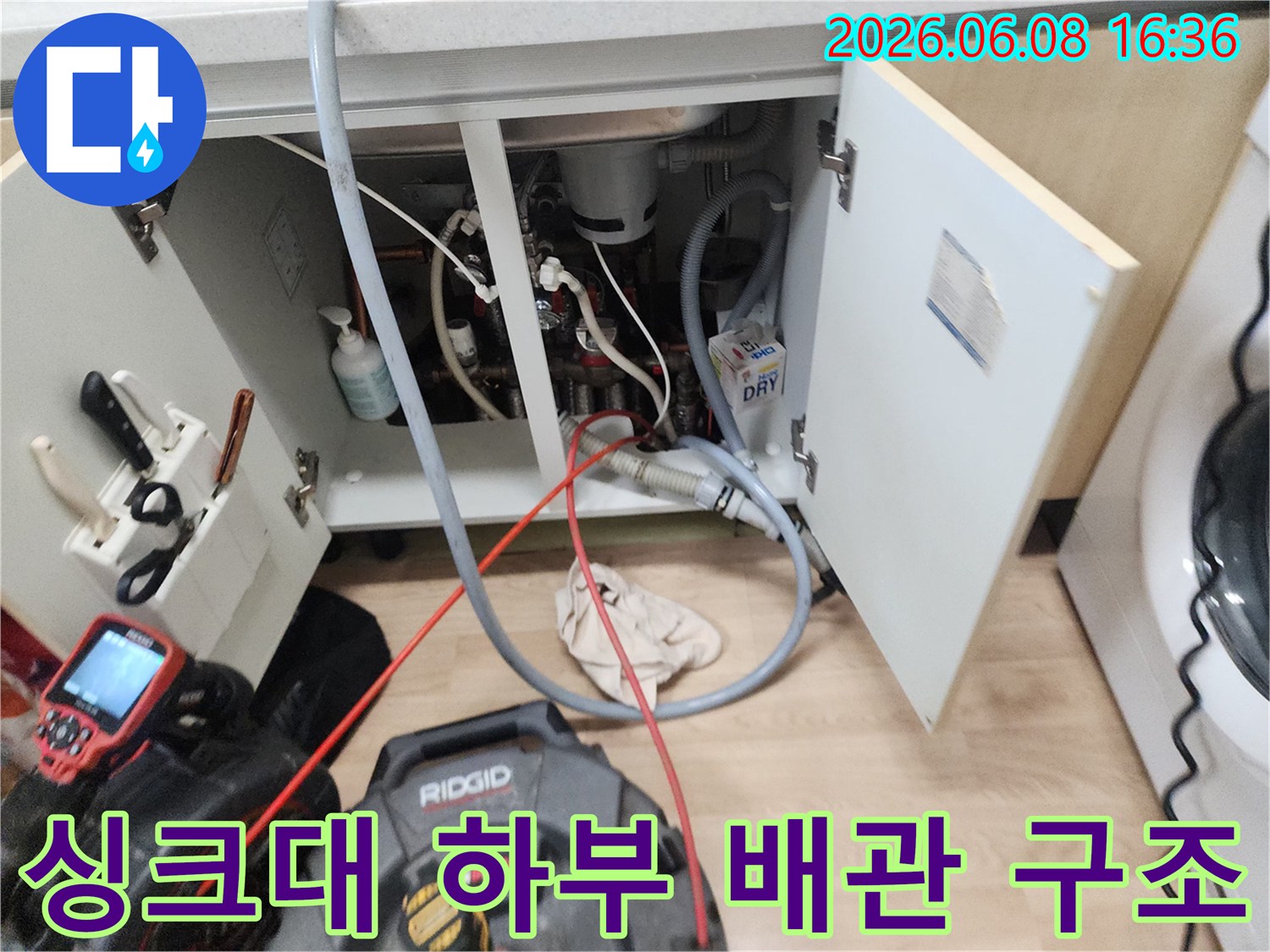 복잡하게 얽힌 싱크대 배관과 작업용 모니터가 보이는 현장 사진입니다.