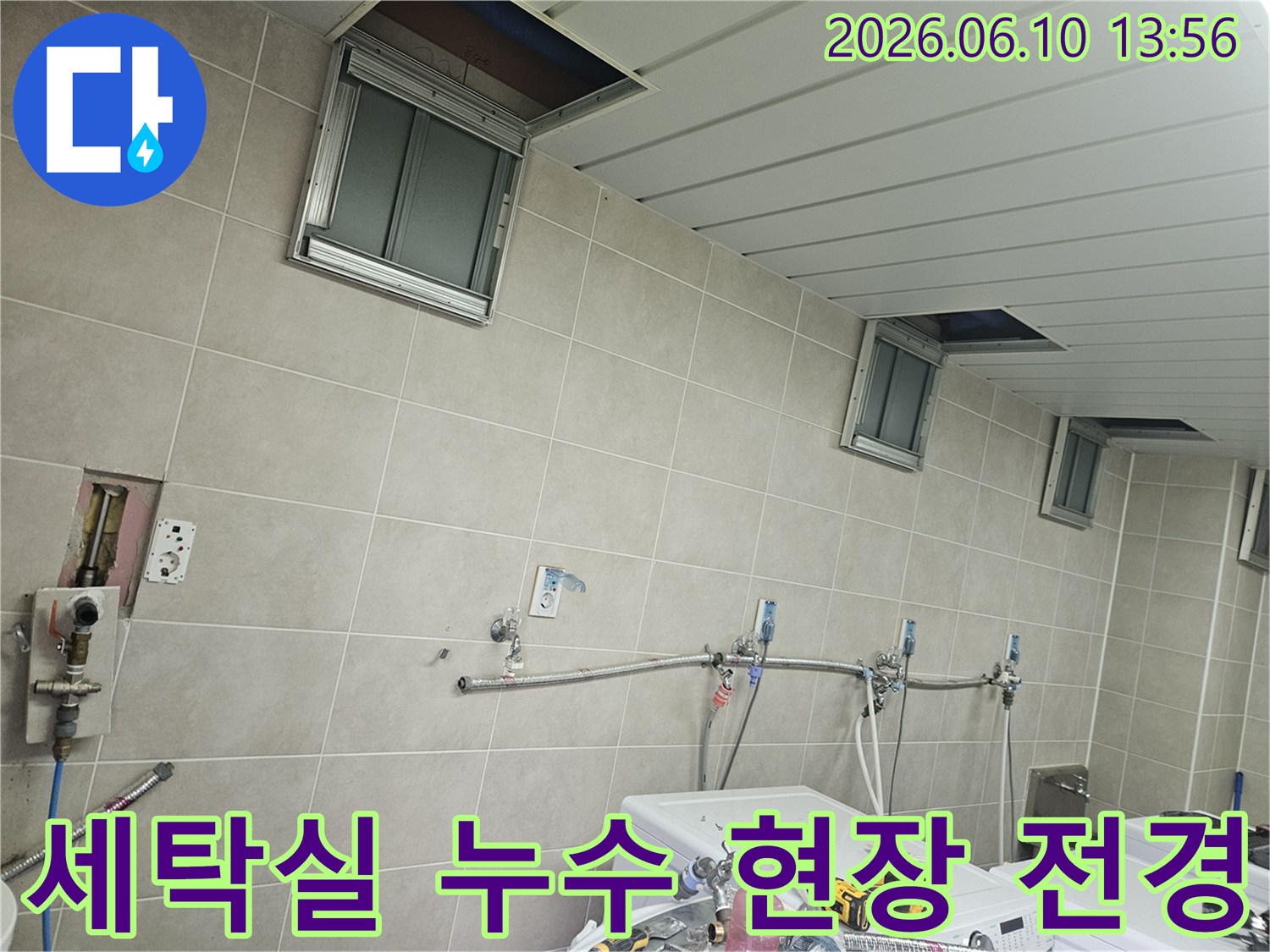 세탁기 여러 대가 놓인 세탁실에서-천장 점검구를 열고 누수 원인을 찾는-작업 현장의 전반적인 모습