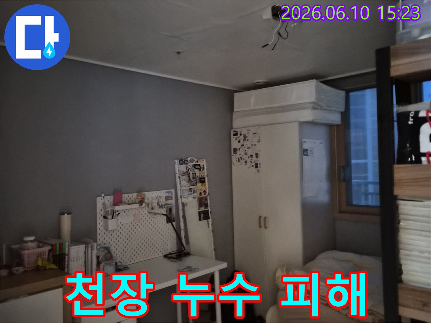 방 천장에 물이 새어 얼룩이 지고 전등 주변 전선이 노출된 모습-누수와 전기 안전 문제가 동시에 우려되는 상황