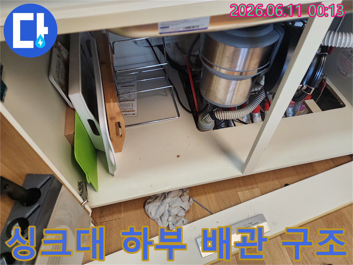 싱크대 하부장 내부의 꼬여 있는 배수 호스와 연결 장치들