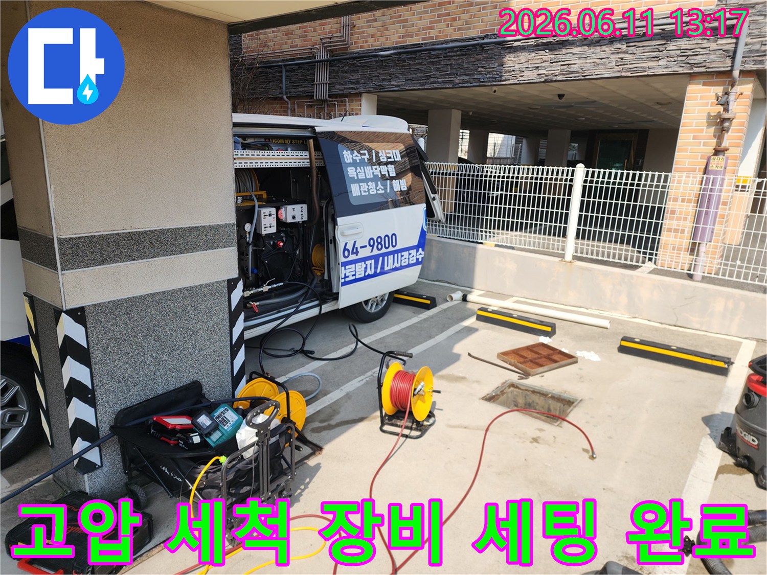 현장 맨홀 근처에 준비된 고압 세척기 및 노란색 호스 릴