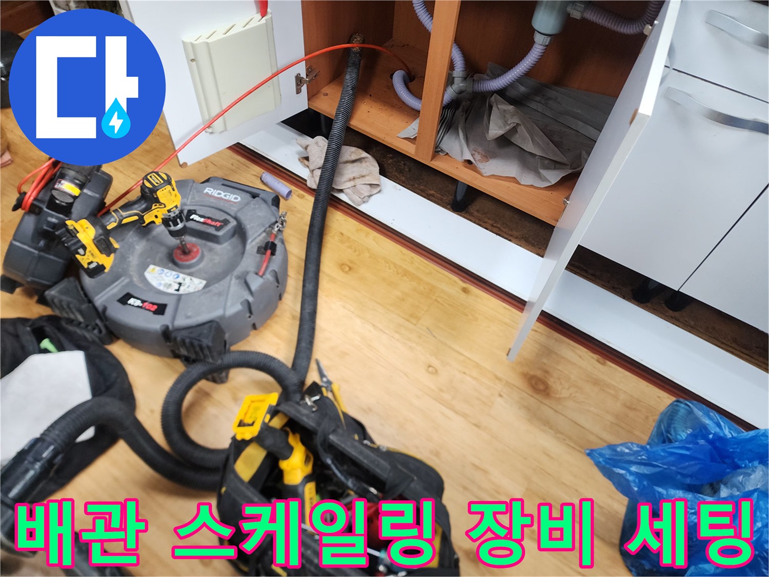 하부장 아래 배관 막힘 해결을 위해 배치된 리지드 전동 드릴과 스프링 작업 도구