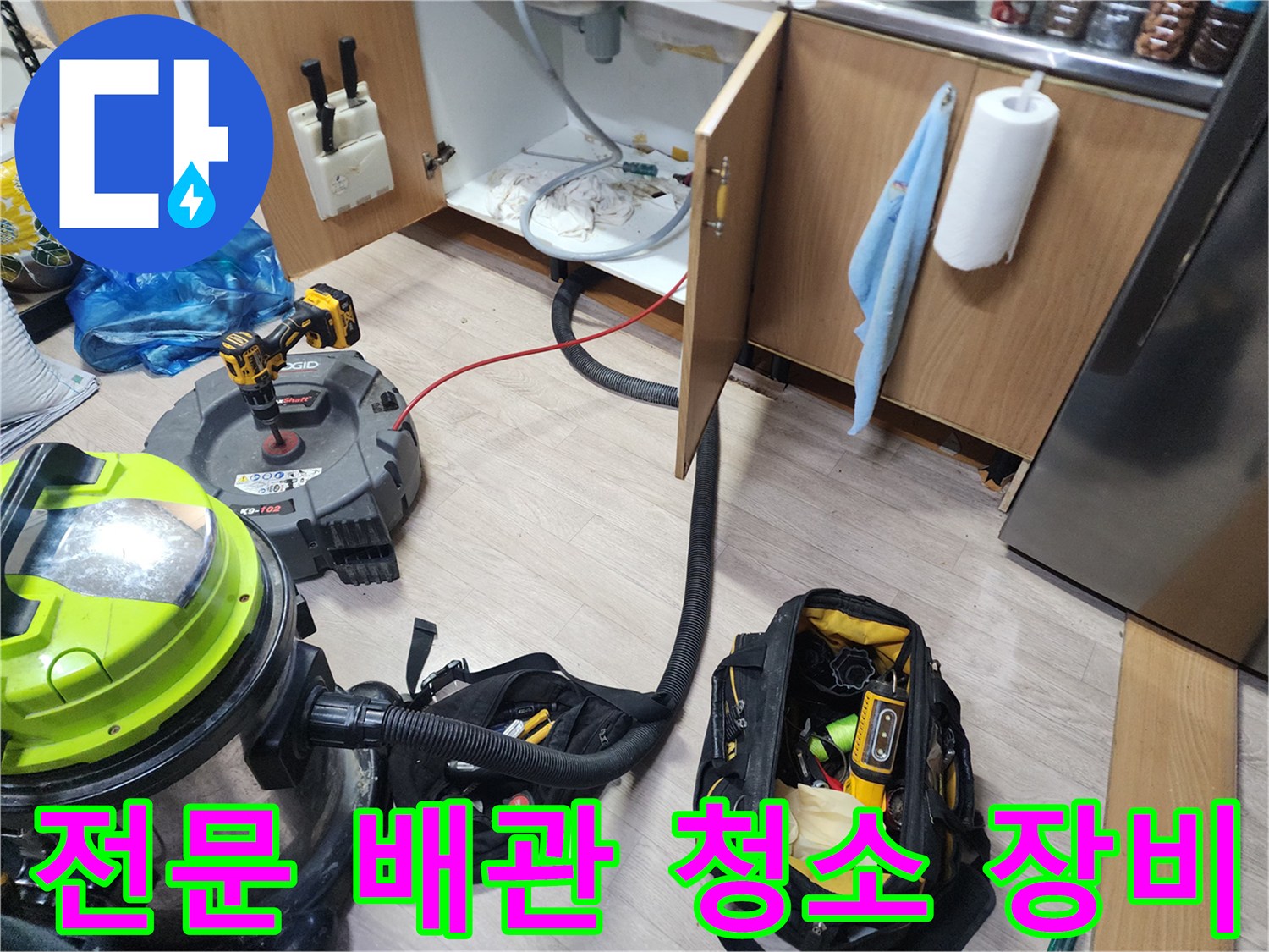 싱크대 밑 배관 작업을 위해 배치된 석션기와 전문 공구 가방