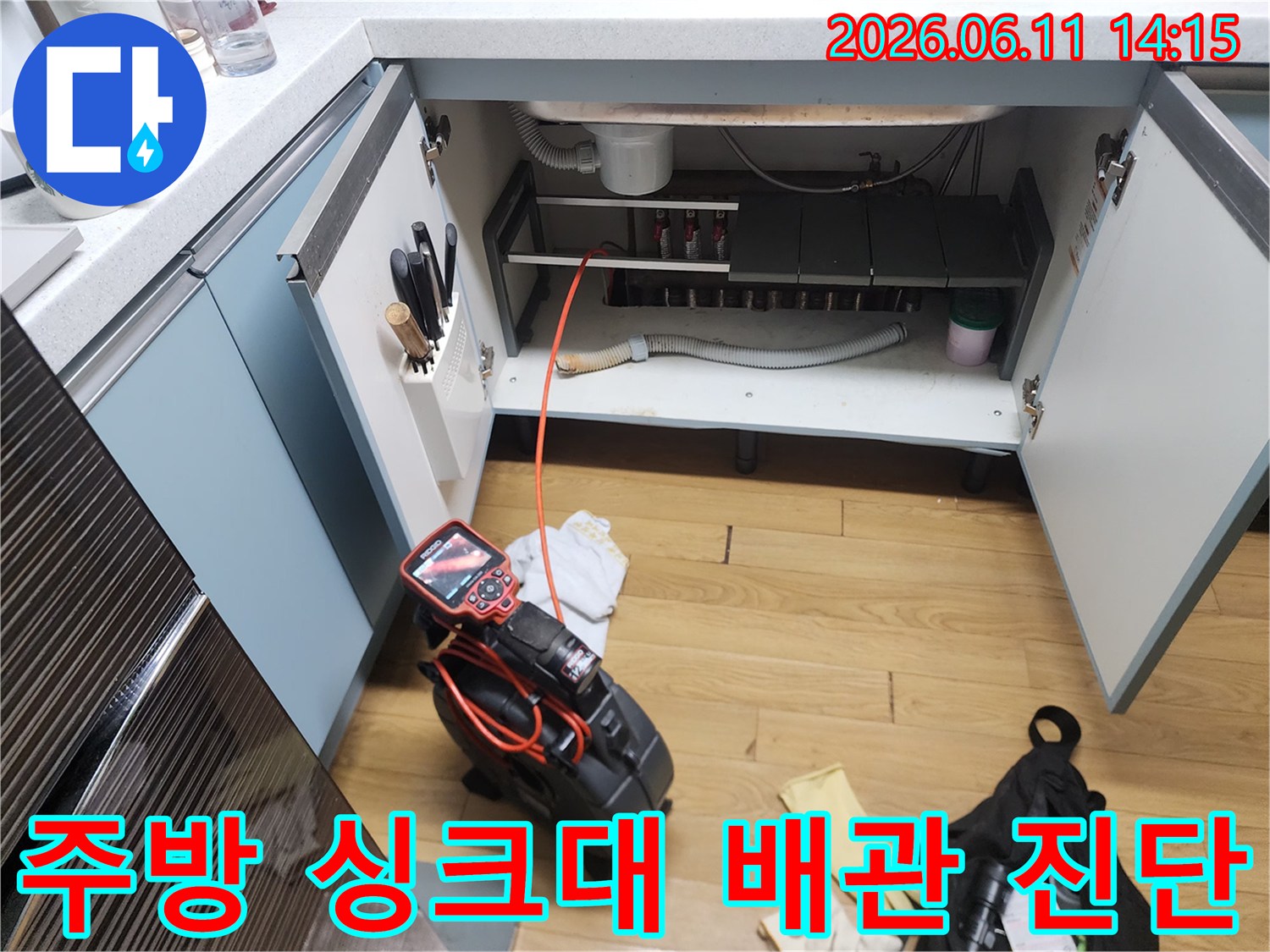 싱크대 하부장 내부의 배수관과 점검용 내시락 장비 모습입니다.