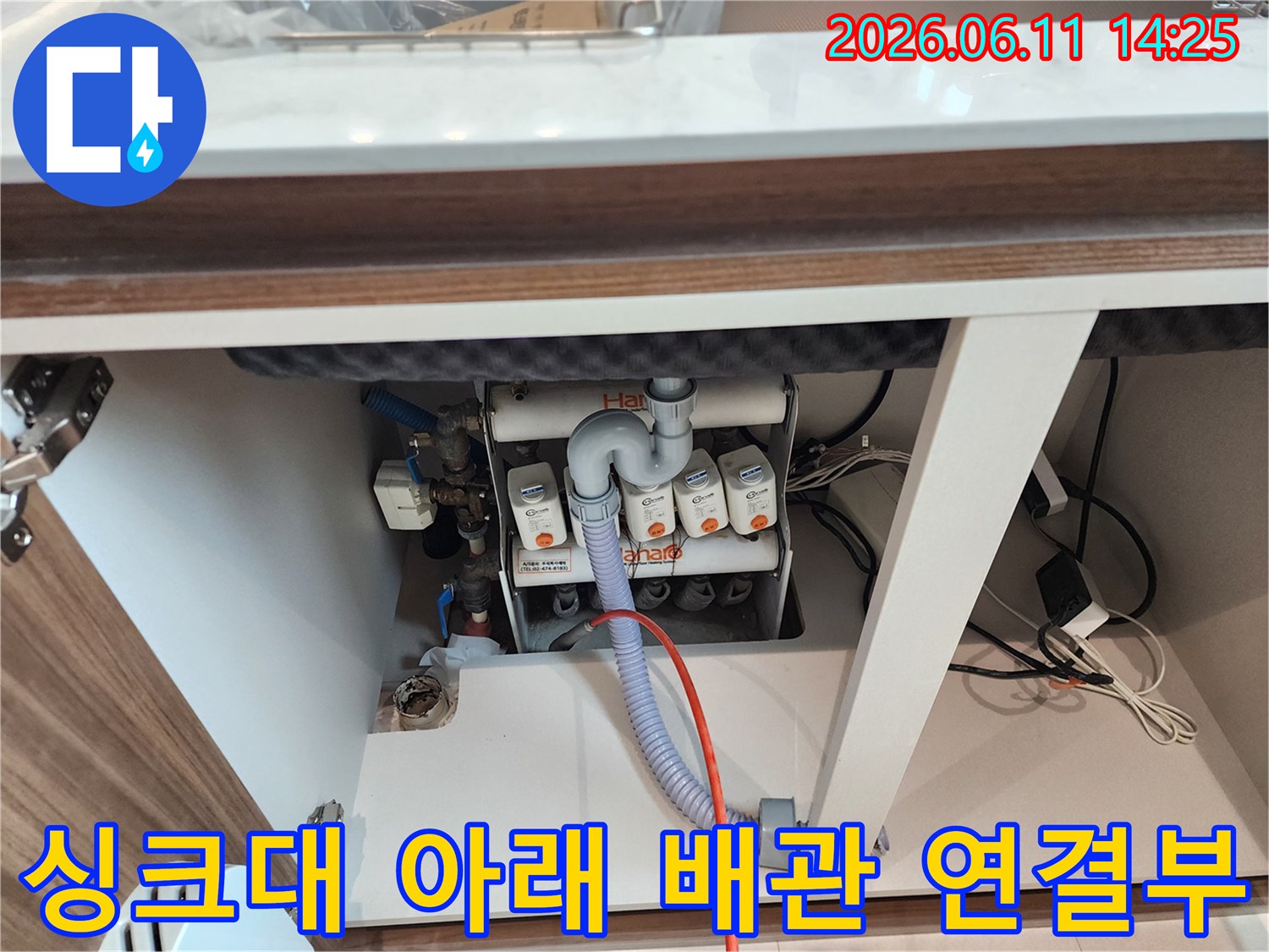 싱크대 하단부의 복잡하게 얽힌 흰색 및 자색 배수 호스들