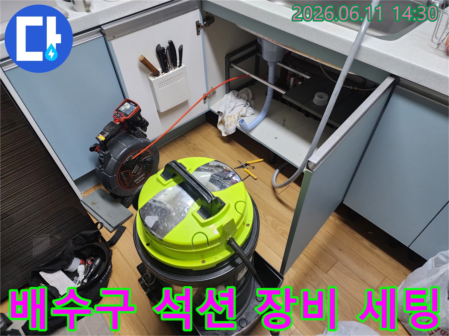 주방 배수관 막힘을 해결하기 위해-석션기와 전동 도구가 싱크대 밑에 배치되어 있습니다.