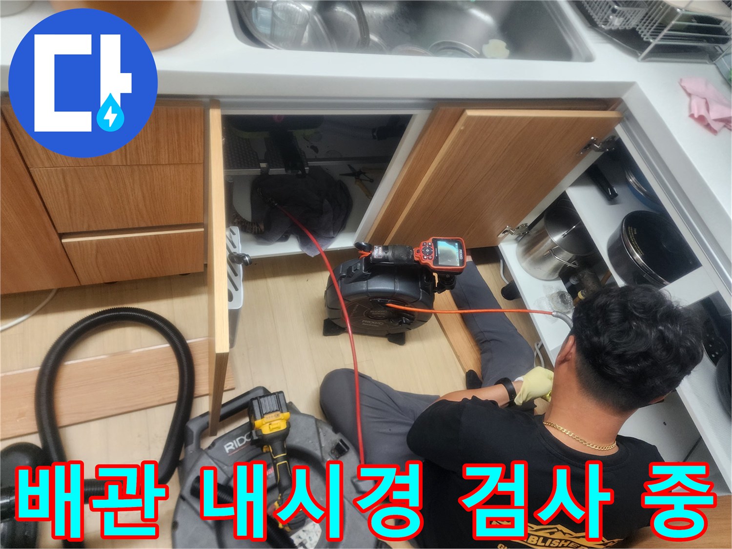작업자가 싱크대 밑에서-배관 내부를 관찰하기 위해-내시경 장비를 운용하는 장면