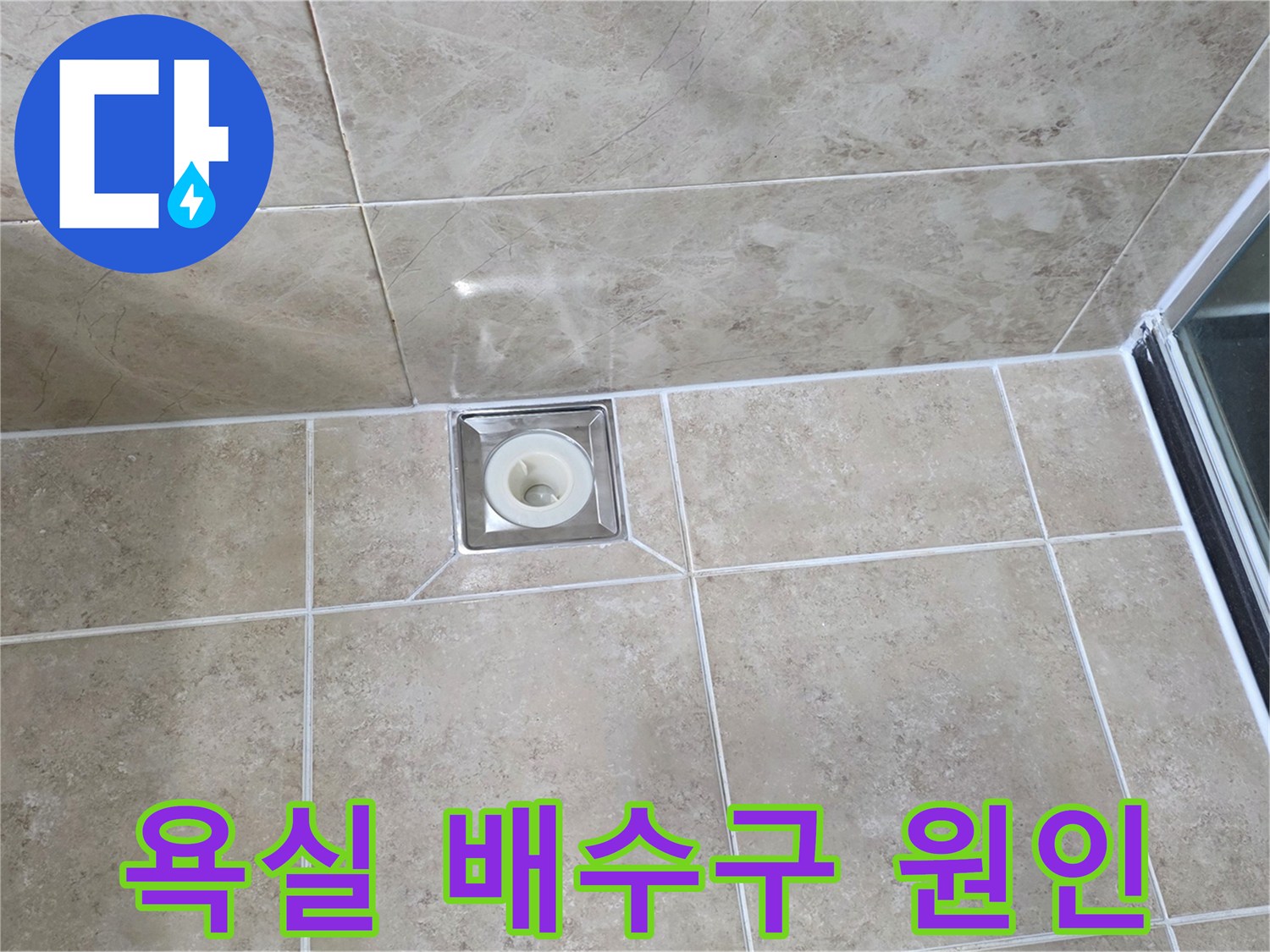 깨끗하게 시공된 욕실 타일 중앙에-사각형 배수구가 위치하며-주변 마감 상태를 면밀히 관찰하는 사진입니다