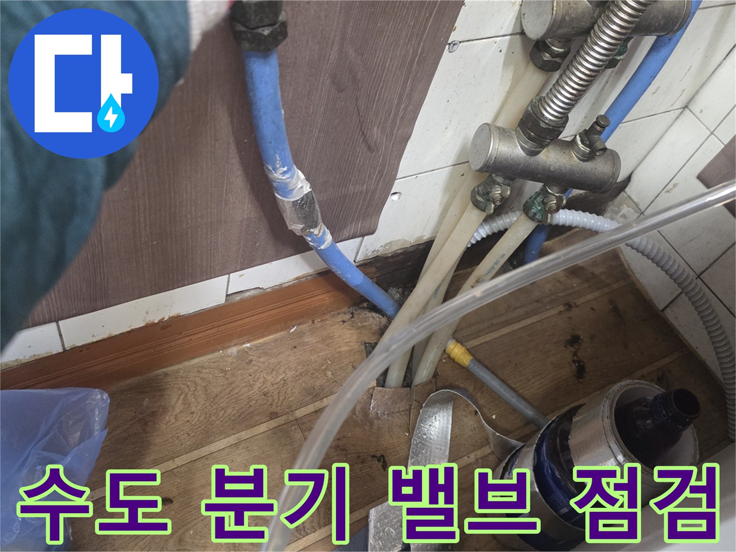 금속 재질의 밸브와 파란색 유연 호스가 연결된 주방 하부 배관 사진입니다.