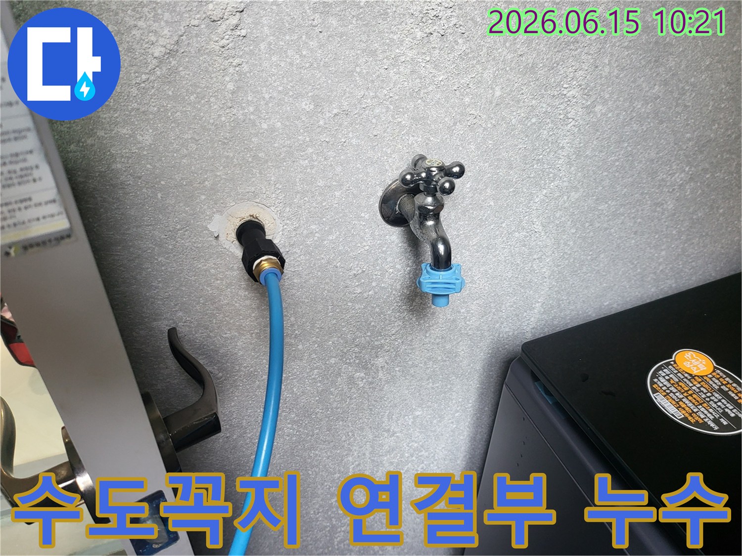 회색 벽에 설치된 수도꼭지와 파란색 호스-연결부에서 발생한 누수를 점검하는 모습