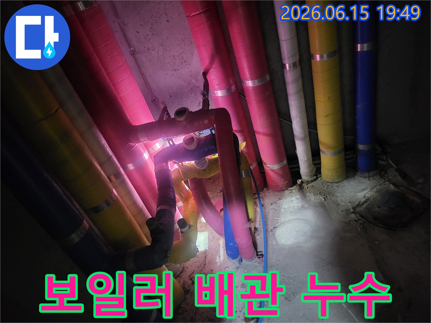 지하-공간에-설치된-다양한-색상의-보일러-관련-배관들을-전문-엔지니어가-누수-여부를-확인하기-위해-정밀하게-살펴보는-모습입니다