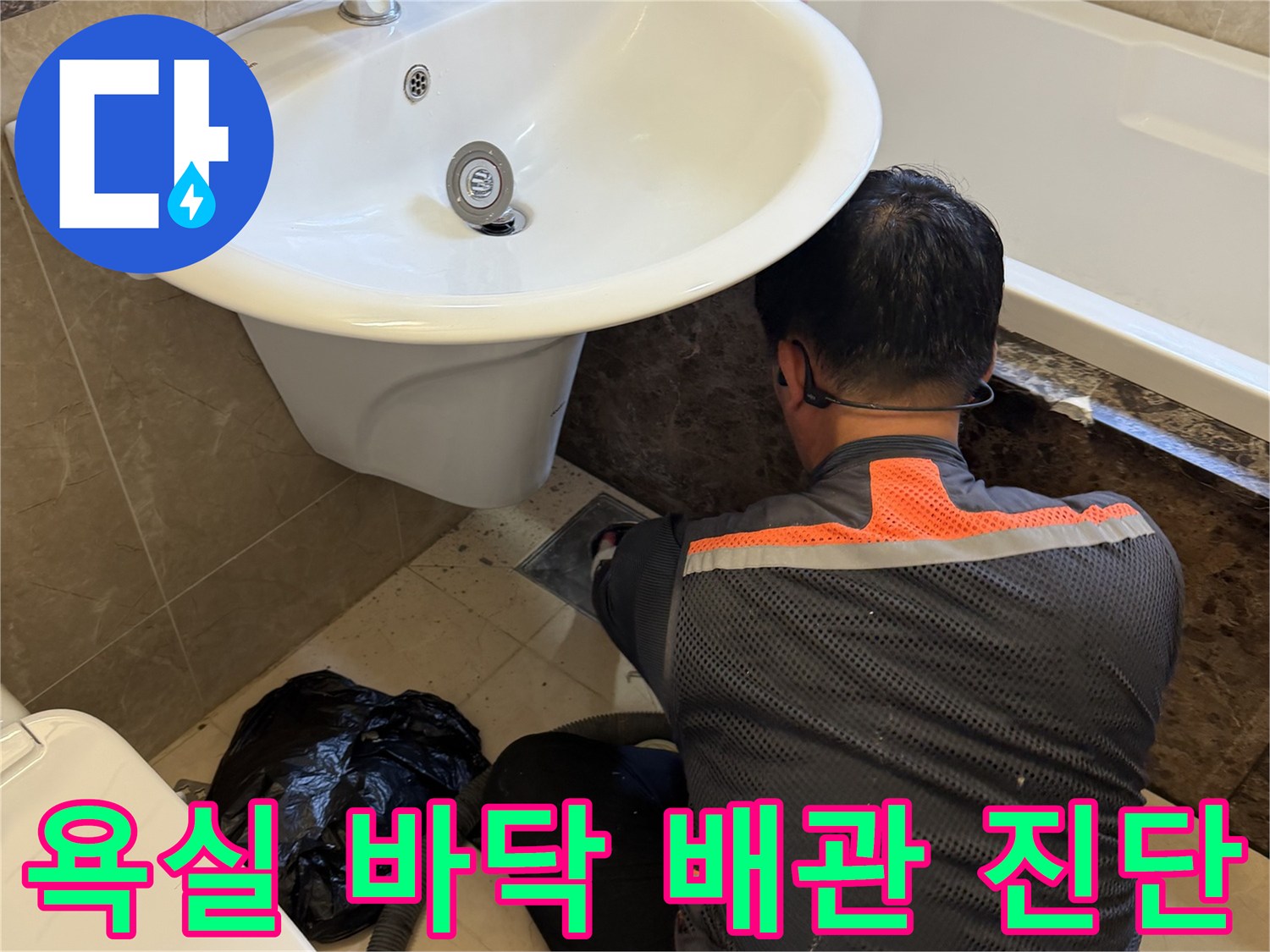 작업자가 세면대 하단 타일 틈새를 조사하며 누수 지점을 찾고 있습니다