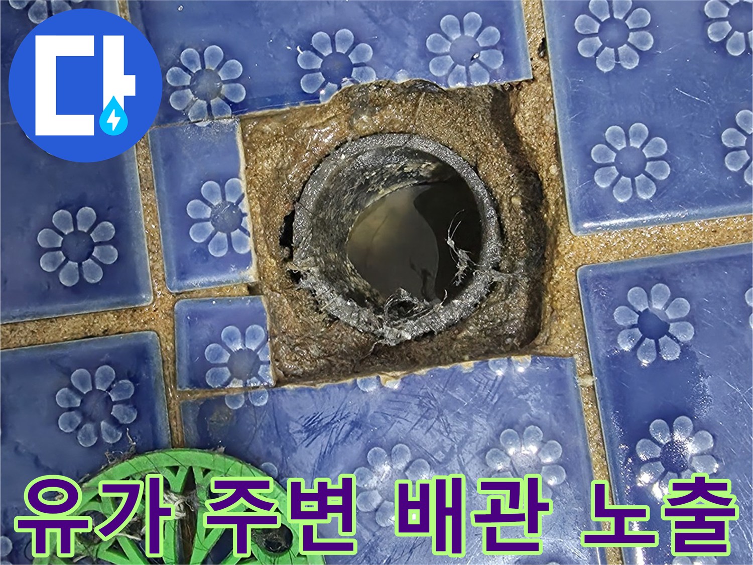 푸른색 패턴 타일 사이로 드러난 하수 배관의 연결 부위