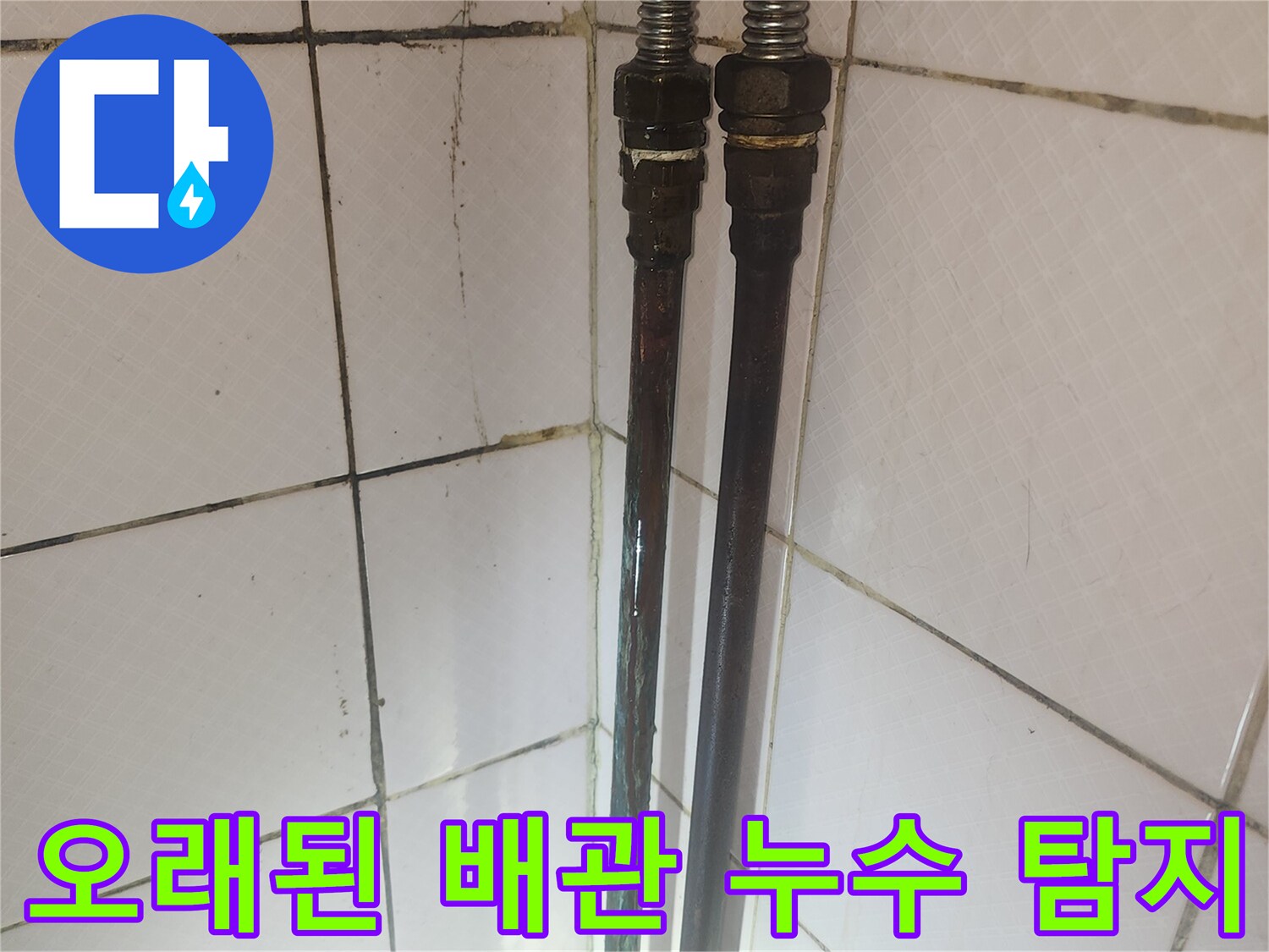 오래된 배관의 연결 부위와 주변 타일의 상태를 보여주며-누수 탐지 과정의 일부입니다