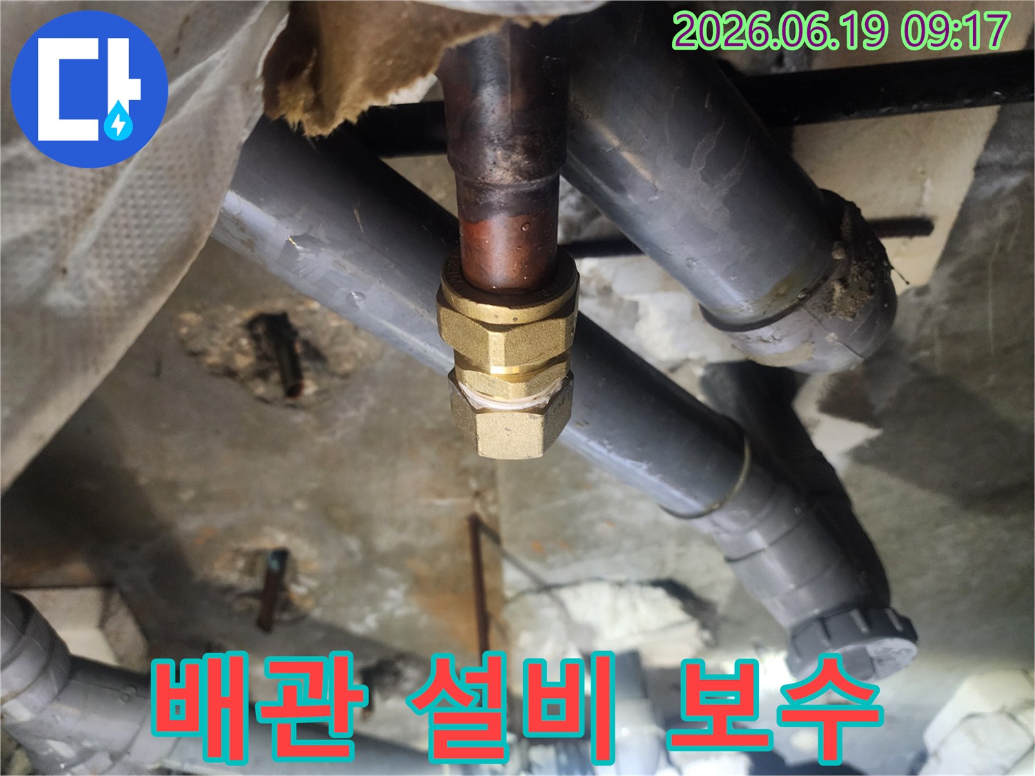 이 이미지는-천장 내부의-오래된 배관 설비에서-발생한 누수를-새로운 황동 부품으로-교체하여-보수하는-전문적인-과정을-보여줍니다.