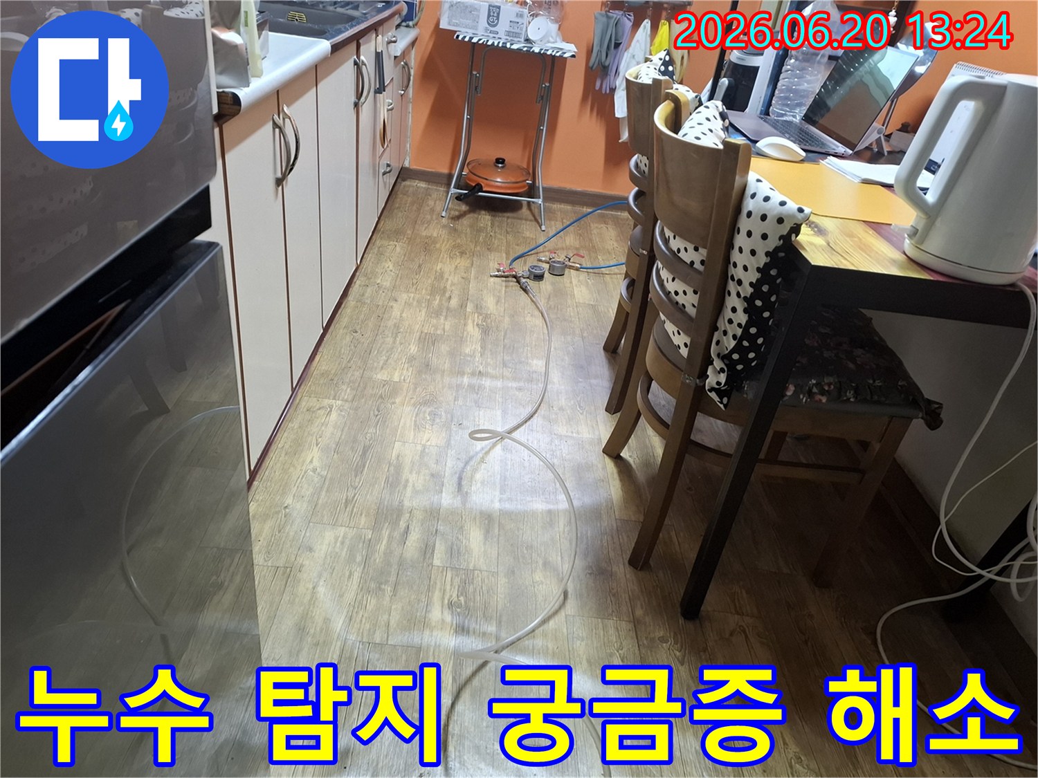 주방 바닥에 설치된 누수 탐지 장비와 함께-고객님의 궁금증을 해소하기 위한 설명을 준비하고 있습니다.