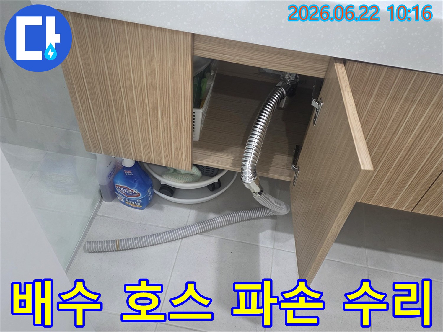 세면대 하부장 아래에서 파손된 배수 호스로 인해 물이 새는-긴급 수리가 필요한 현장