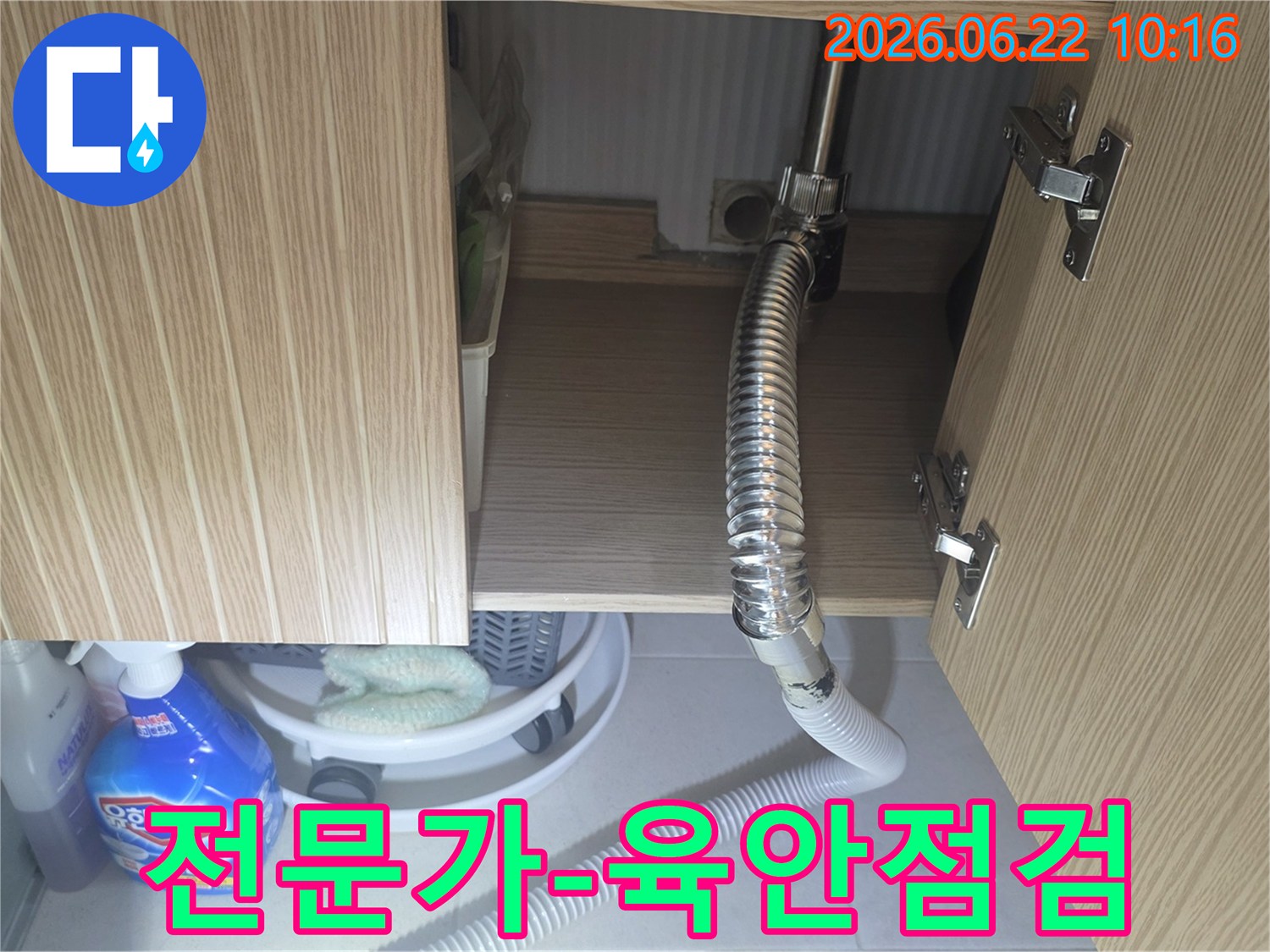 싱크대 하부장 내부의 배관과 호스를 전문가가 육안으로 꼼꼼하게 점검하는 장면