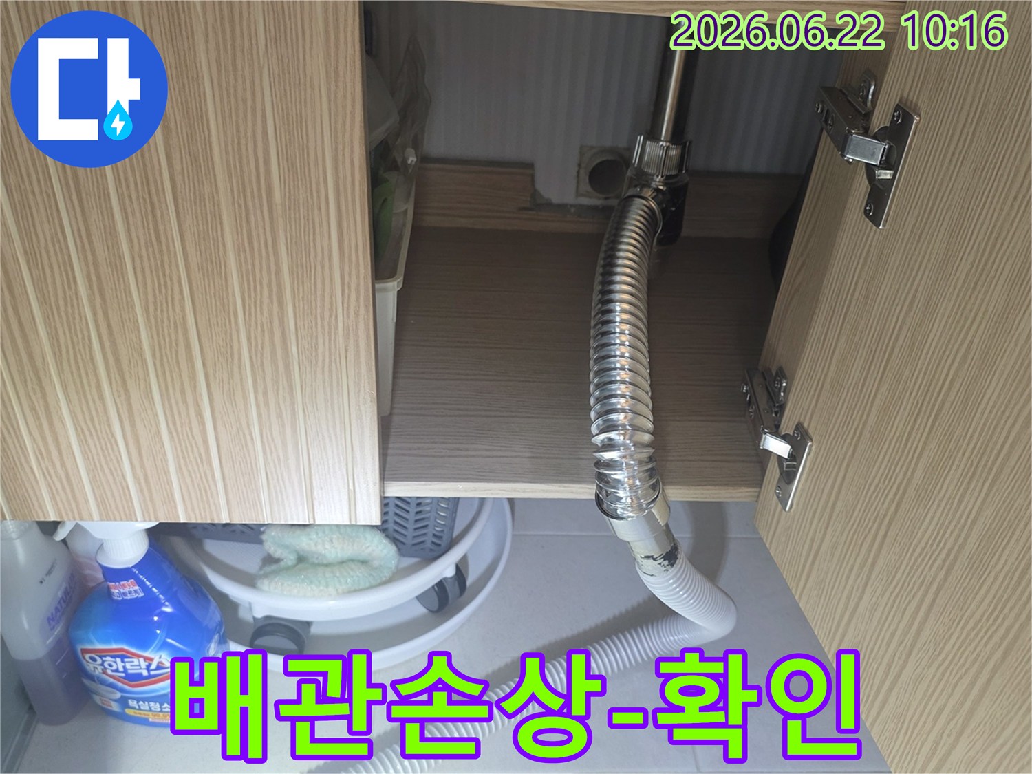 싱크대 하부장 내부의 배관과 호스에 발생한 손상 여부를 면밀히 확인하는 장면