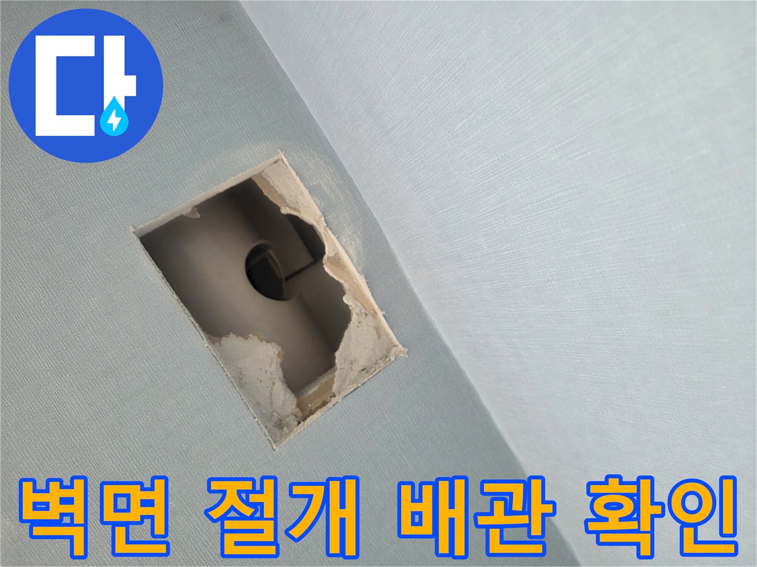 벽면을 사각형으로 절개하여 내부 PVC 배관 상태를 점검하는 모습입니다.