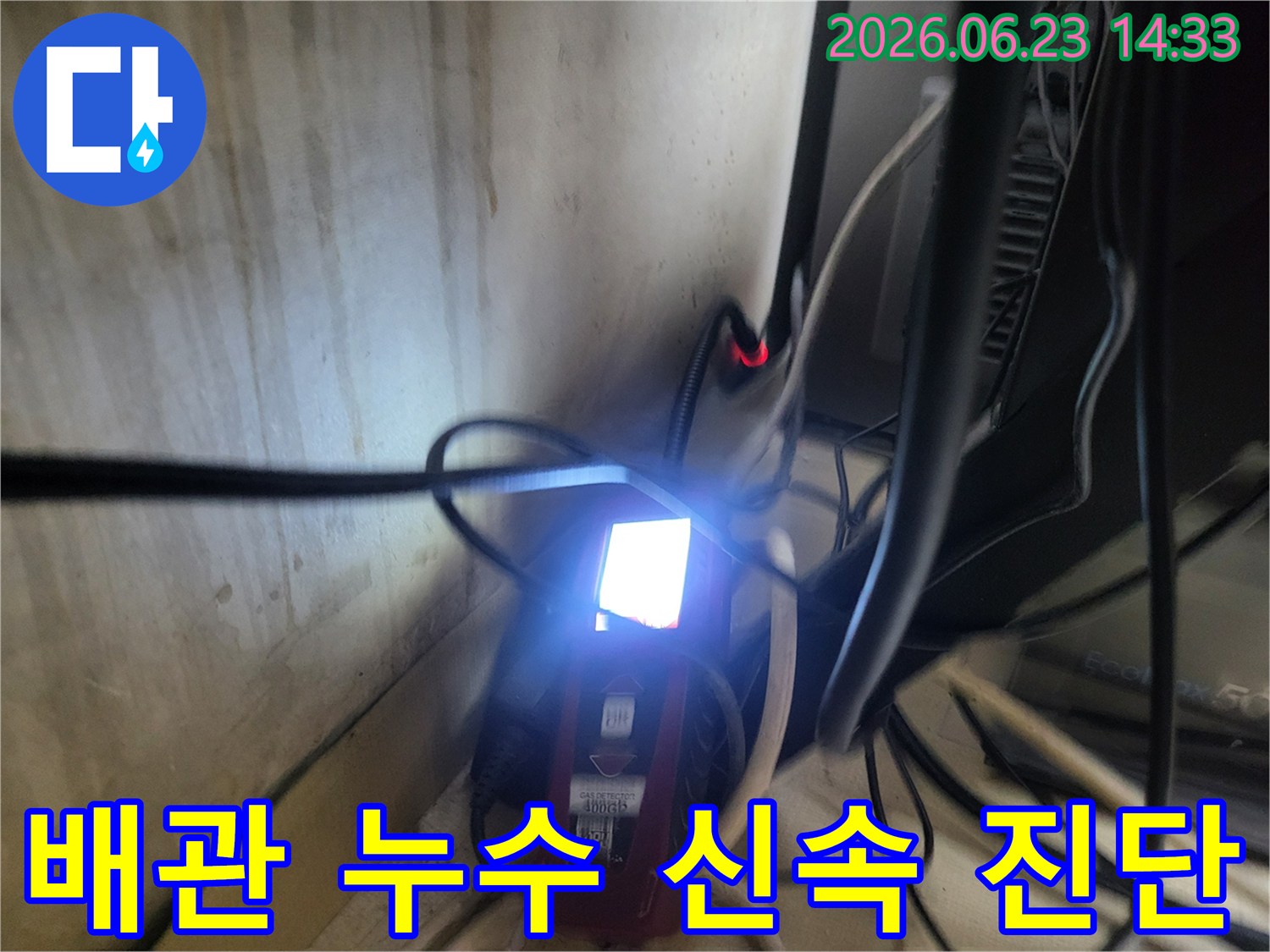 어두운 구석의-복잡한 배관 사이에서-누수탐지 장비가-작동하는 장면