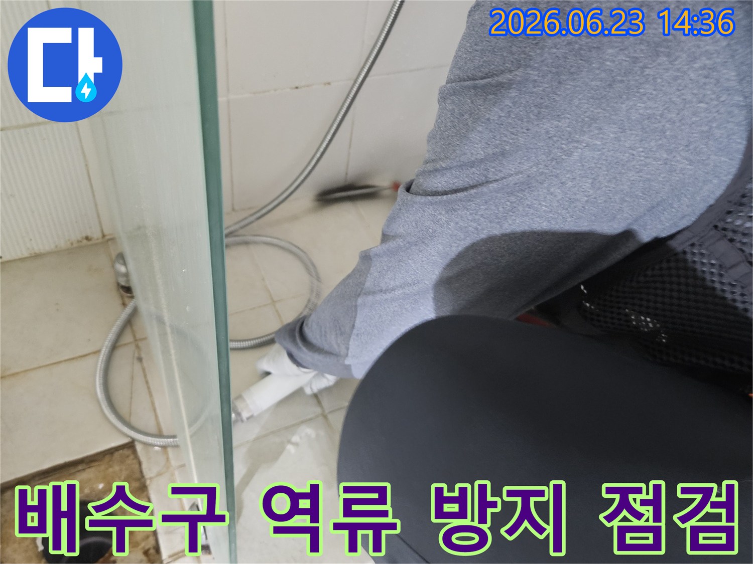 전문 엔지니어가-욕실 바닥의 배수구에서-역류로 인한 누수 발생을 막기 위해-정밀하게 점검하고 있습니다.