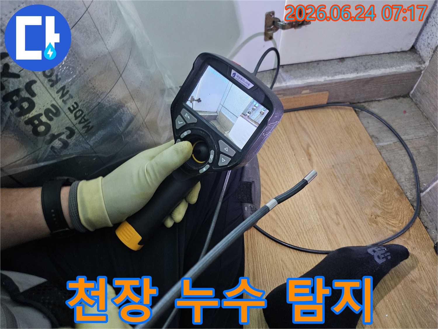이 이미지는-숙련된 기술자가-누수 문제를 해결하고자-내시경 탐지기로-숨겨진 배관의 상태를 확인하는 과정입니다.