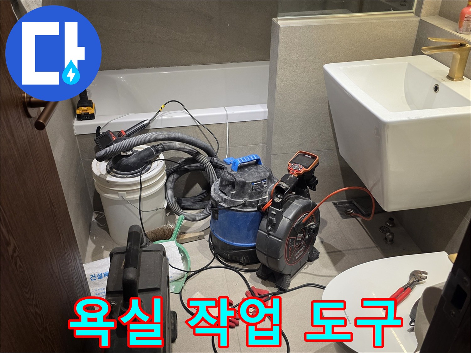 세면대 아래-배관 점검을 위해 준비된 청소기와 공구들
