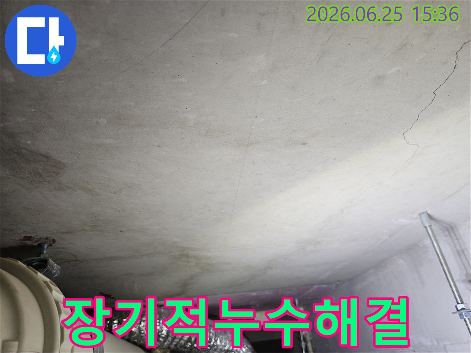 천장 콘크리트 표면에 나타난 물 자국과-배관 주변의 습기 흔적이-장기적인 관점에서 누수 문제를 해결해야 함을 암시하는 현장 사진입니다.