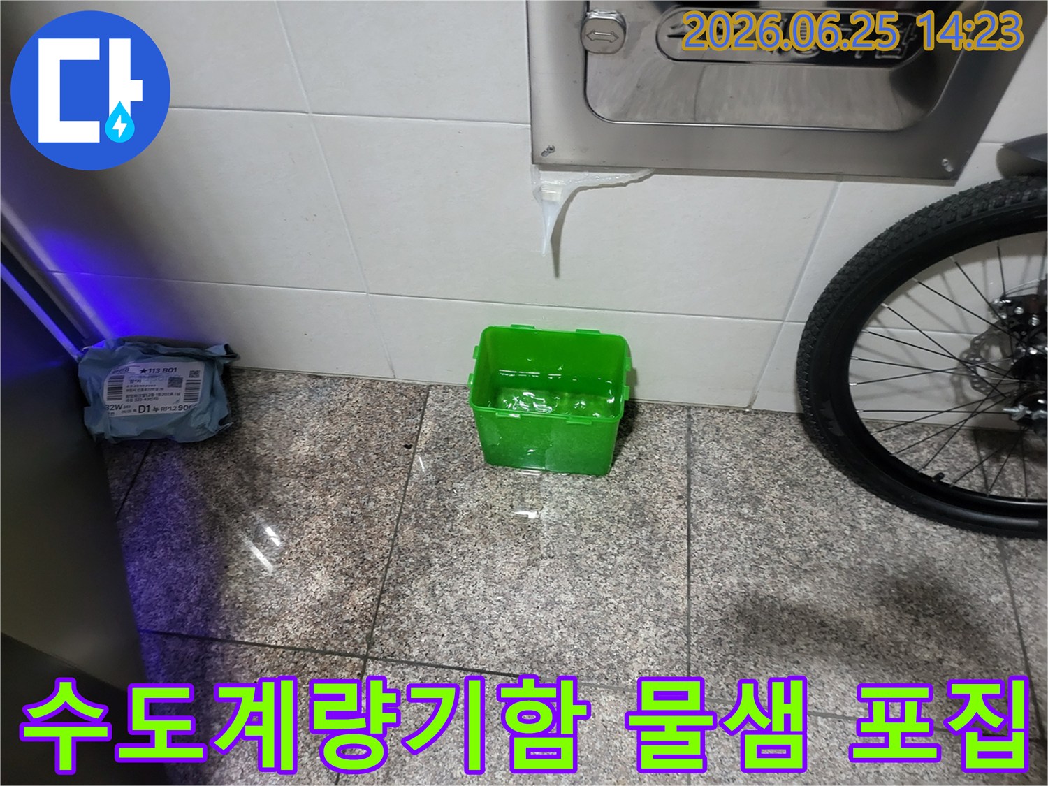 수도계량기함에서-물이-새어-나와-초록색-물받이에-고이는-장면을-촬영한-사진