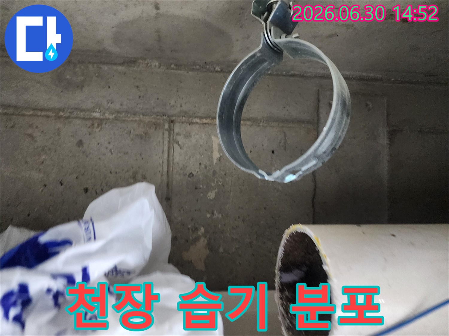 콘크리트 천장에 보이는-넓은 습기 자국과-배관 고정 밴드의-누수 현장 전경
