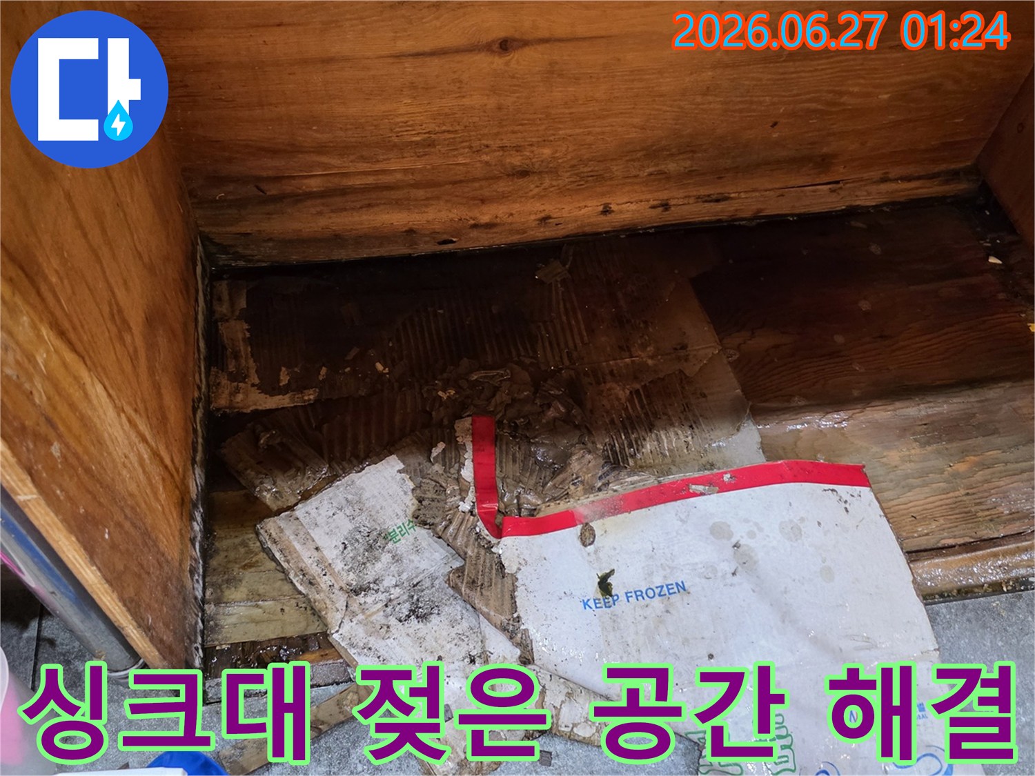 물에 젖어-손상된 종이 상자와-습기로 얼룩진-나무 바닥이-보이는-싱크대 하부의-위생 문제 해결 현장입니다.